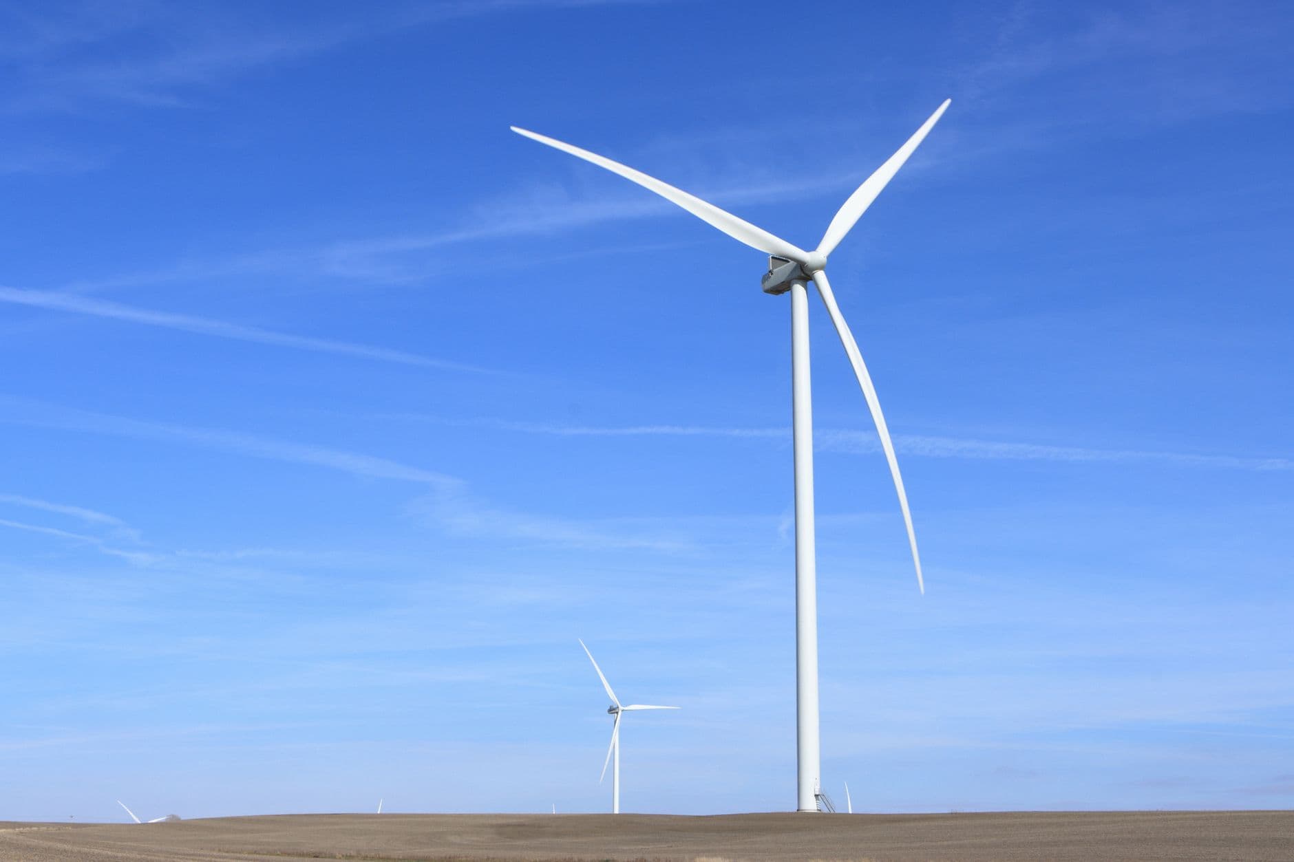 Windturbines op een vlak, kaal veld onder een heldere blauwe lucht