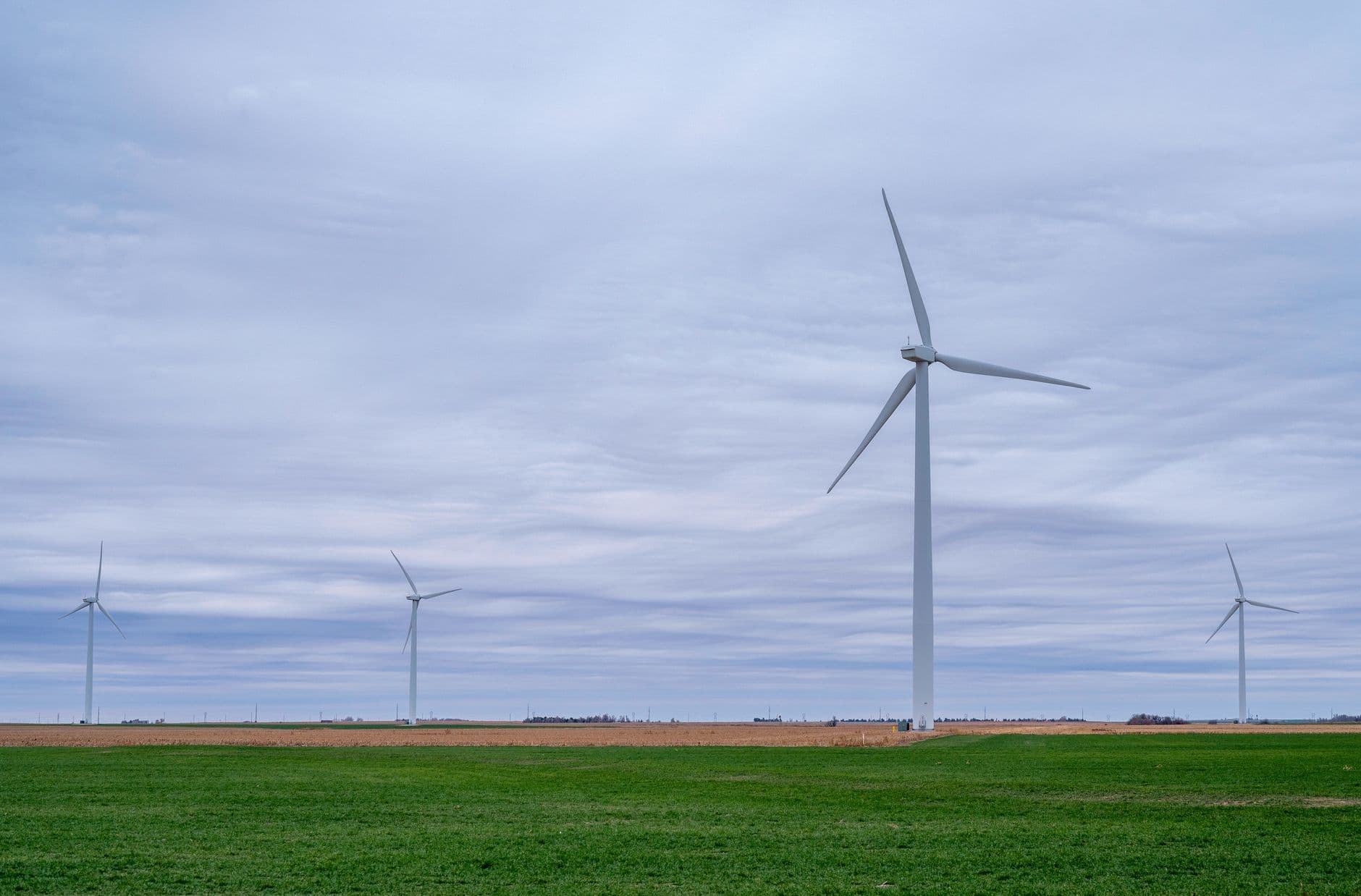 Windturbines op een vlakke groene akker onder een bewolkte lucht