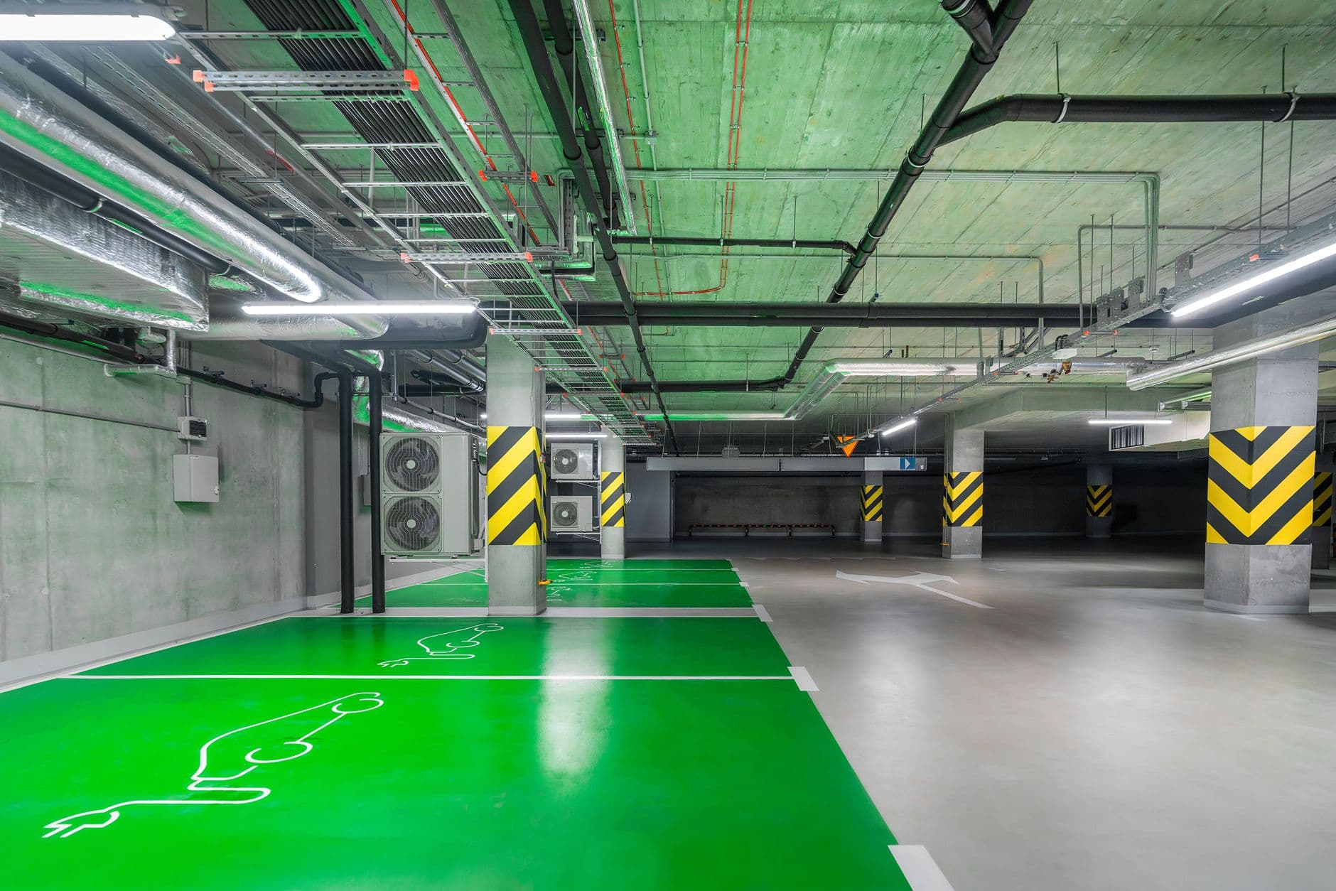 Groen gemarkeerde parkeervakken voor elektrische auto's in een lichte ondergrondse parkeergarage