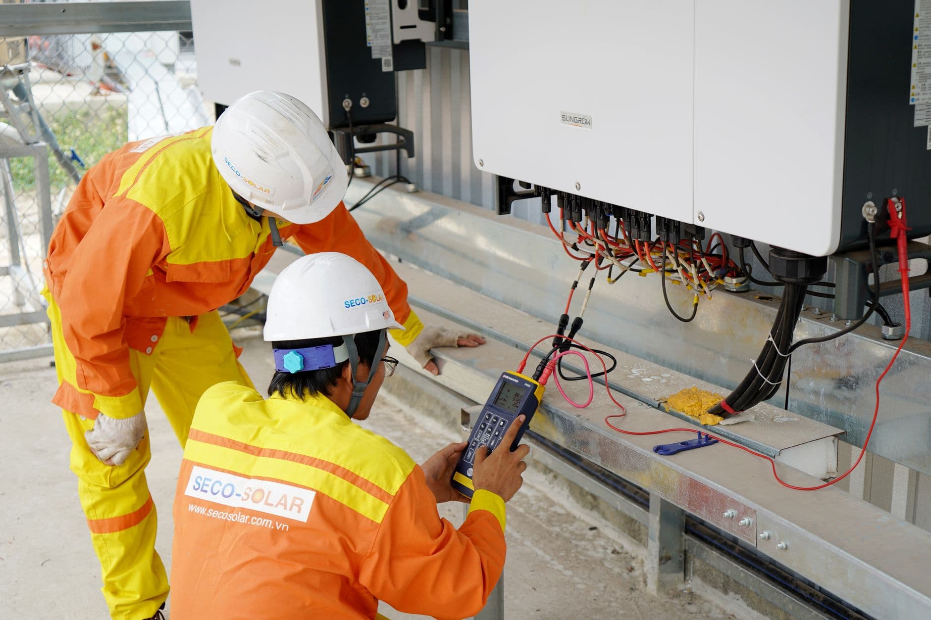 Twee technici met helm testen een installatie voor zonne-energie