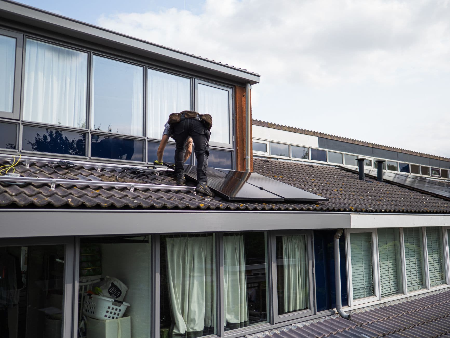 Installateur legt zonnepanelen op een pannendak van een woning