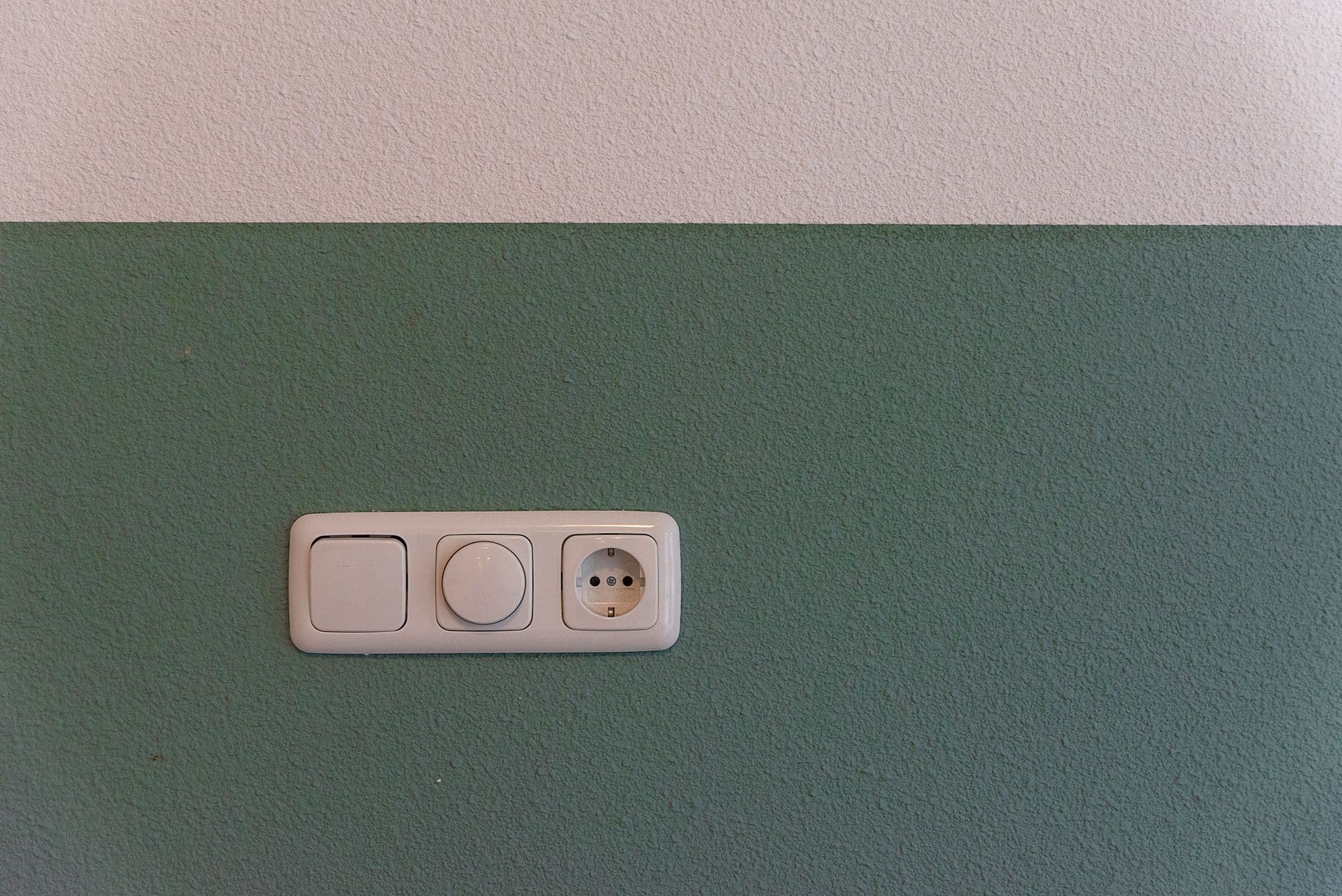Stopcontact met schakelaar en dimmer op een groen geschilderde muur