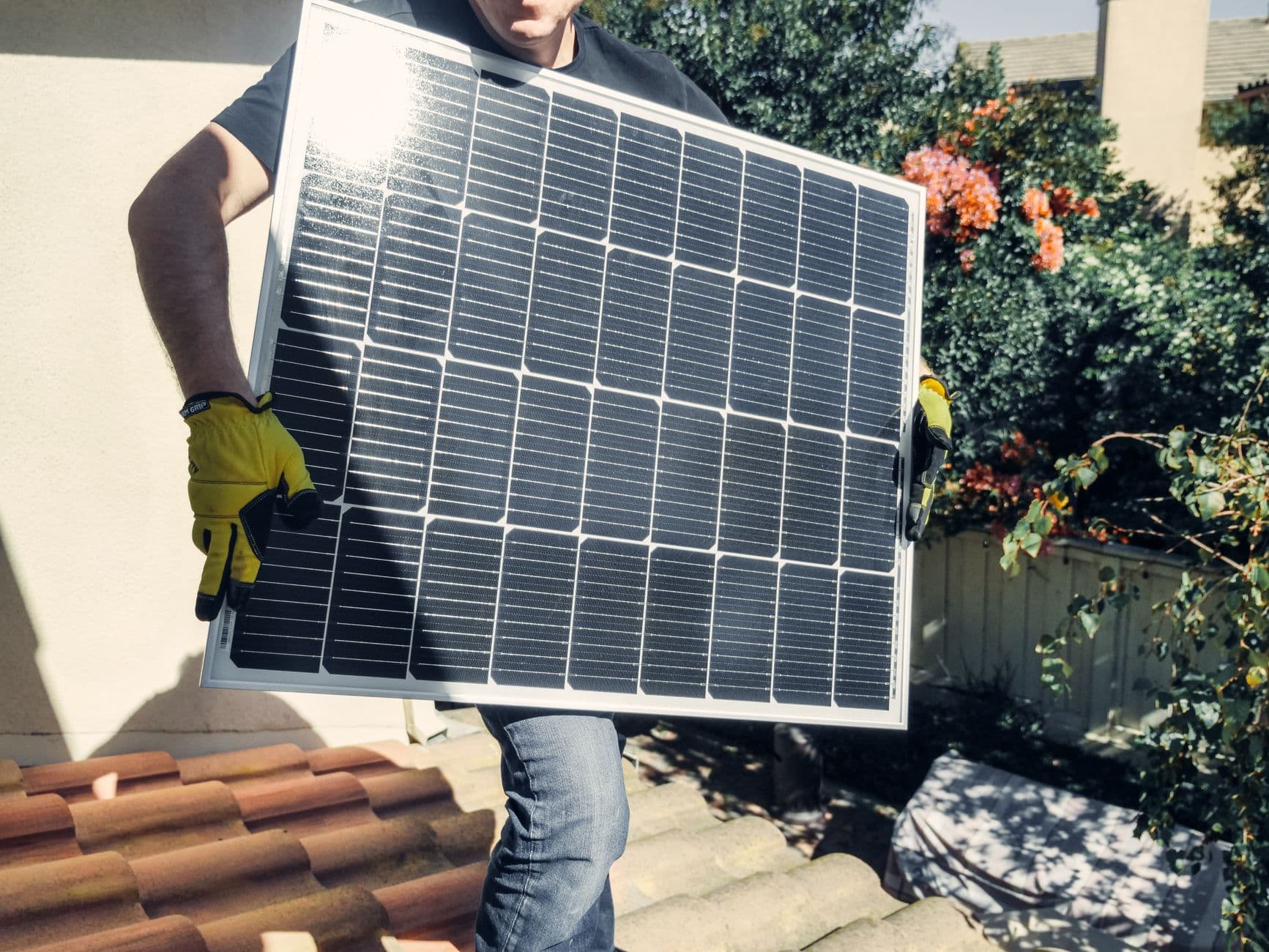 Technicus draagt een zonnepaneel over een dak