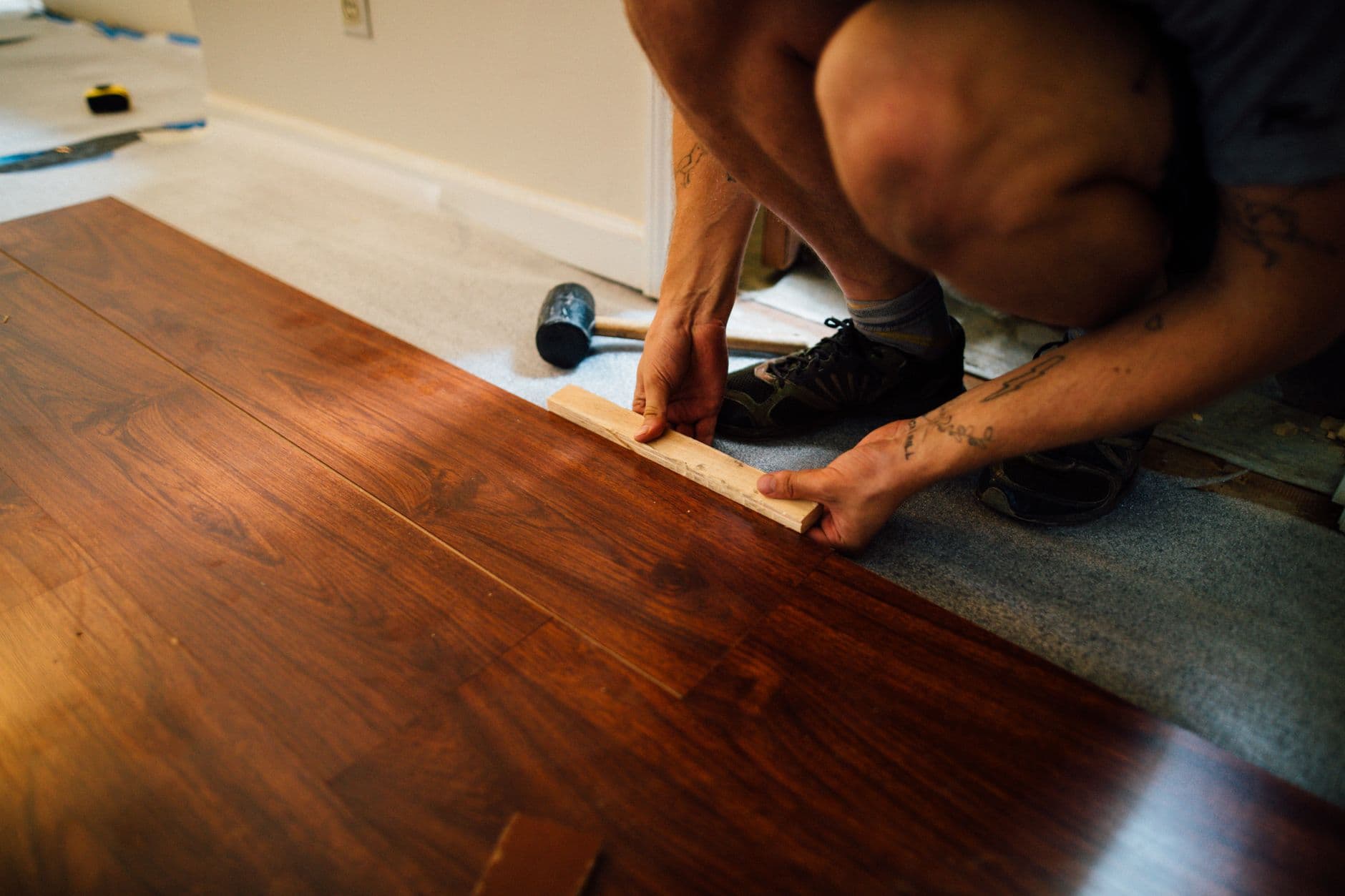 Vakman legt een laminaatvloer met een hamer tijdens een renovatie